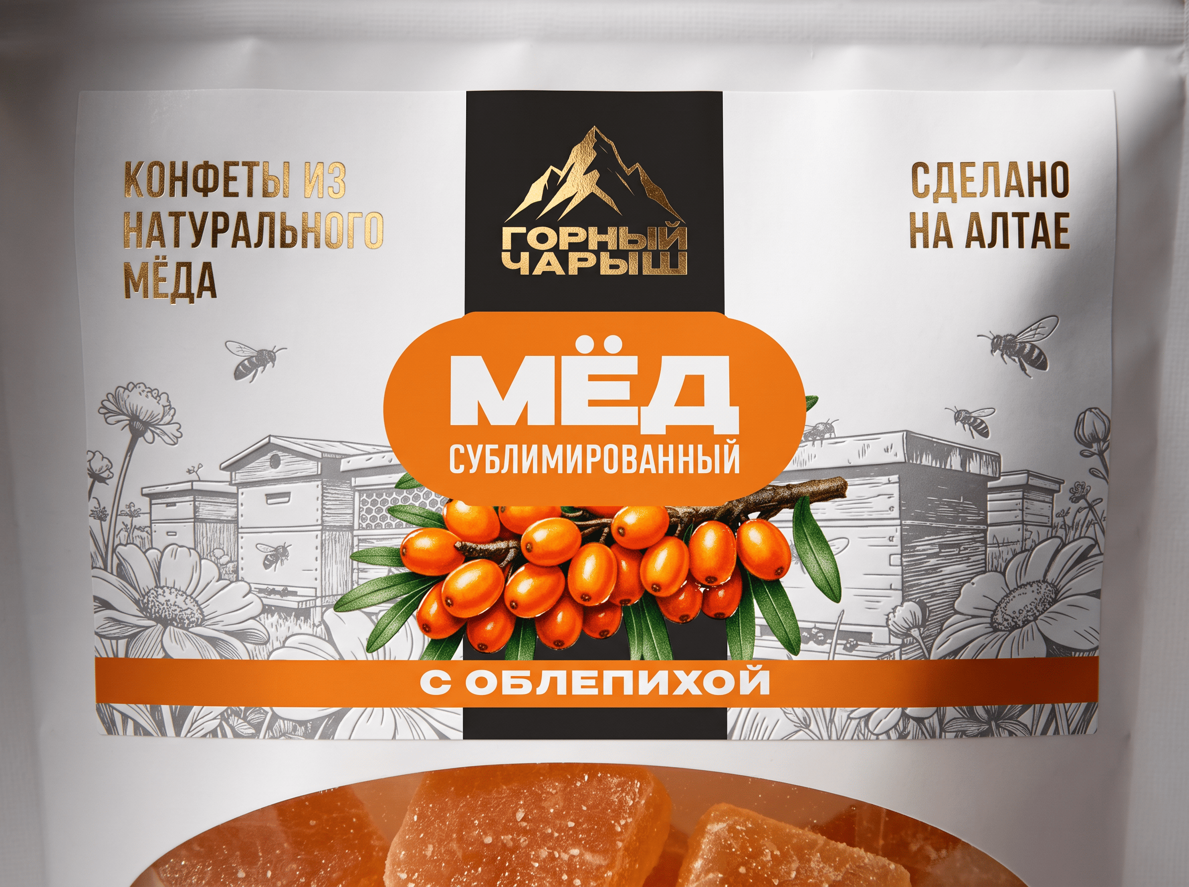 Крупный план упаковки мёда «Горный Чарыш» с облепихой: название продукта и надпись «Конфеты из натурального мёда»
