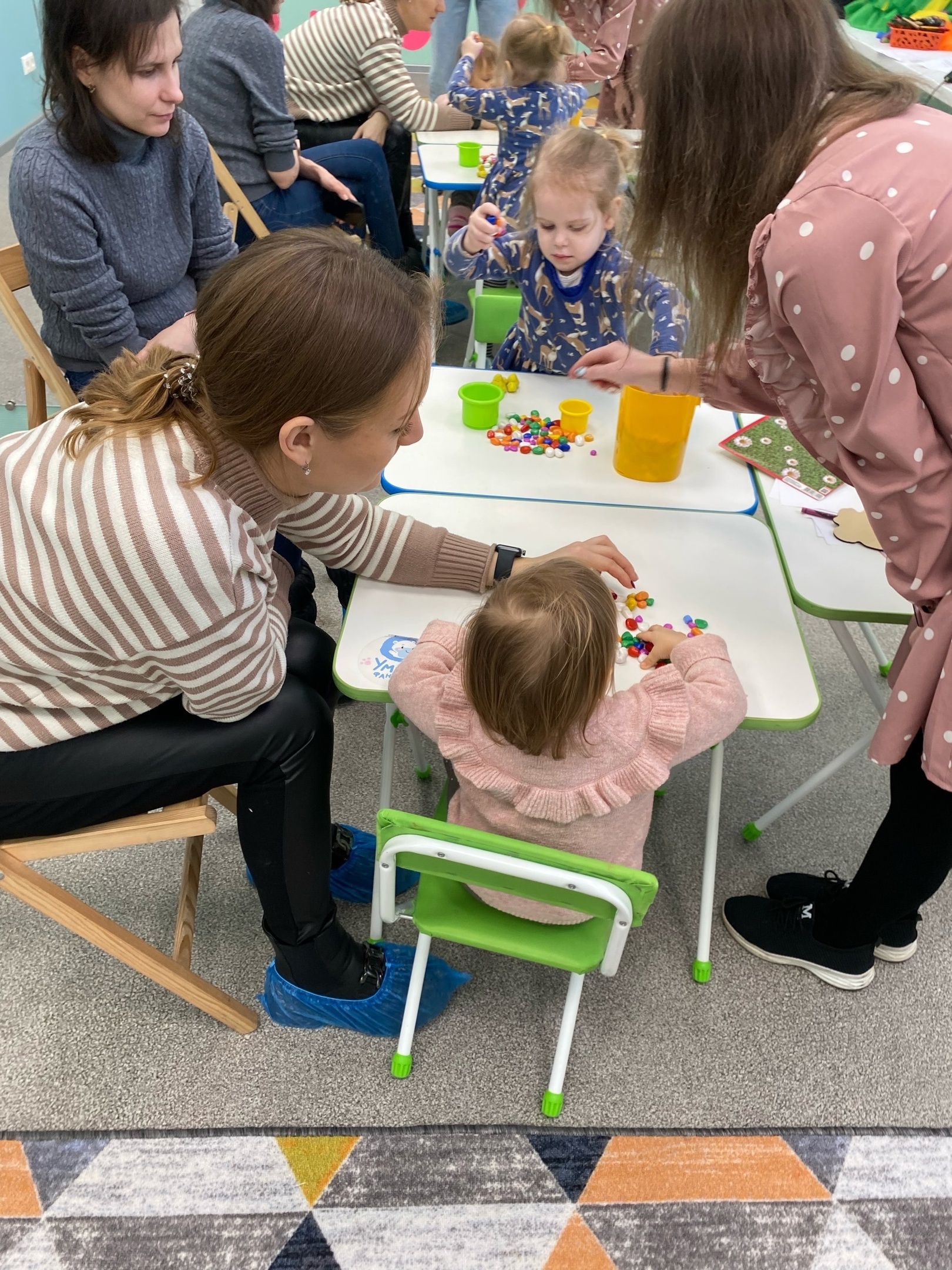 мамы с малышами занимаются аппликацией на занятии по раннему развитию в детском центре
