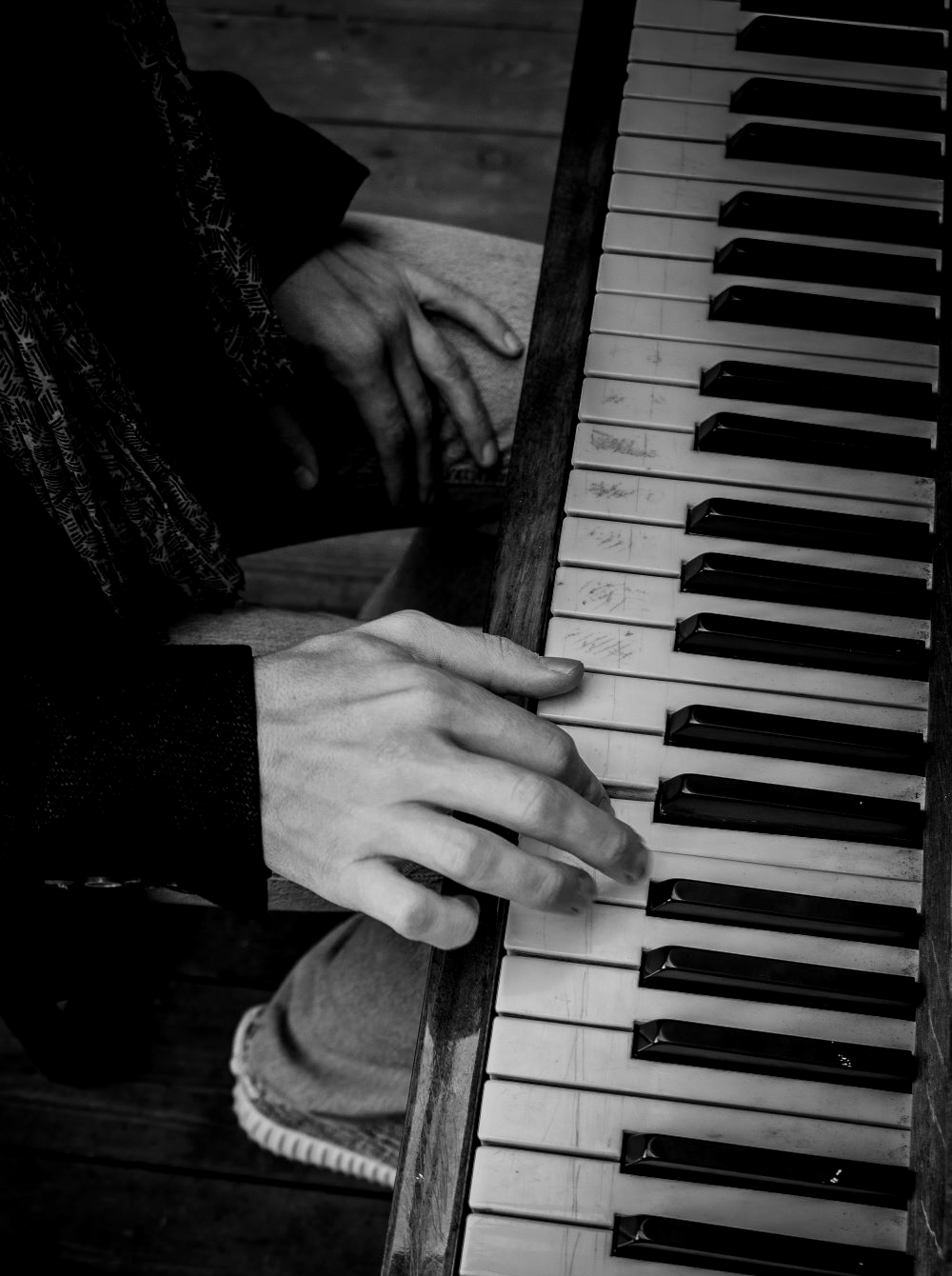 Черное-белое изображение мужчины, демонстрирующего игру на фортепиано 