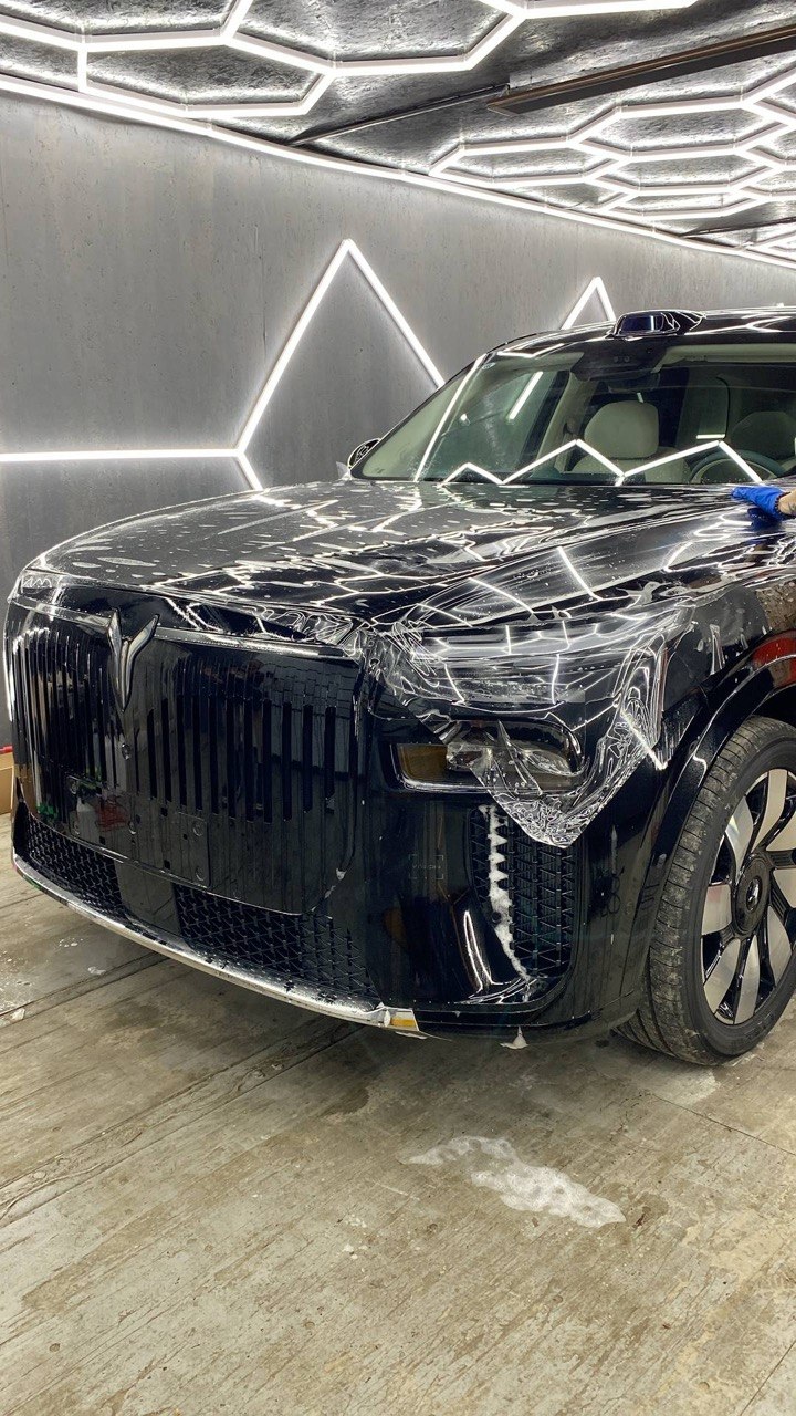 Прозрачная плёнка на передней части чёрного автомобиля
