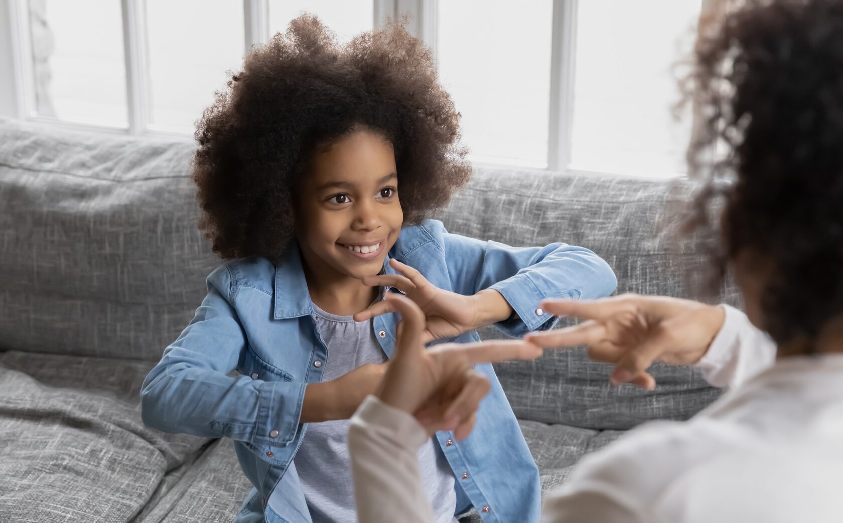 A mixed race child speaking to an adult using sign language