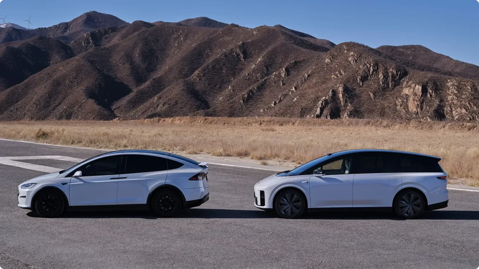 Сравнение: Tesla Model X и Li Auto i8 в белом цвете, вид сбоку на дороге на фоне гор, электромобили в одном классе.