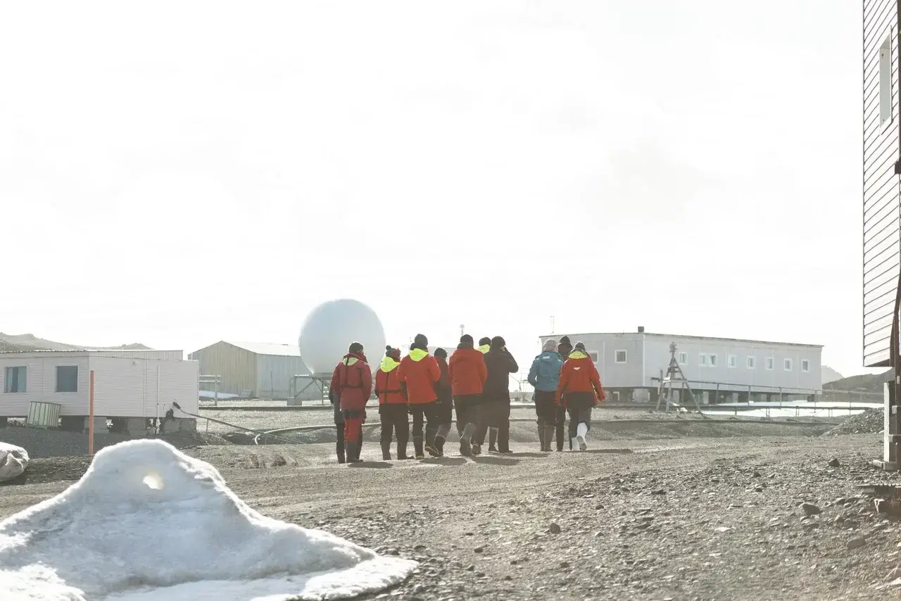 Participants of the MoreTime Expeditions Antarctic Science Camp walk through Bellingshausen Station during a guided tour with polar researchers. Guests explore one of Antarctica's active research stations, learning about everyday life, scientific work, and logistics while experiencing the continent beyond a traditional expedition.