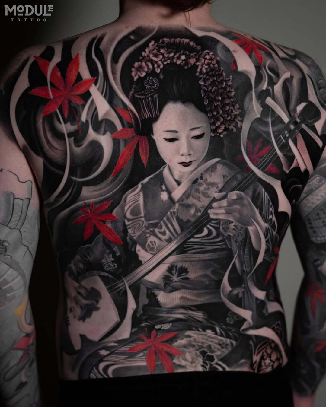 A large-scale back tattoo featuring a realistic portrait of a geisha playing the shamisen, complete with bright red maple leaves and shadows, by Rinat Mingazdinov, Los Angeles, West Hollywood