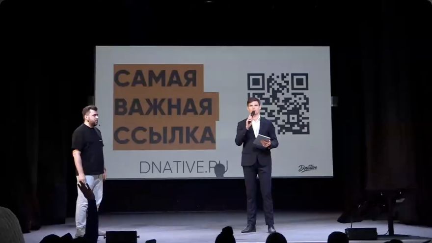 Ведущий с микрофоном и Алексей Ткачук на сцене конференции МТС Маркетолога; кадр из официальной трансляции