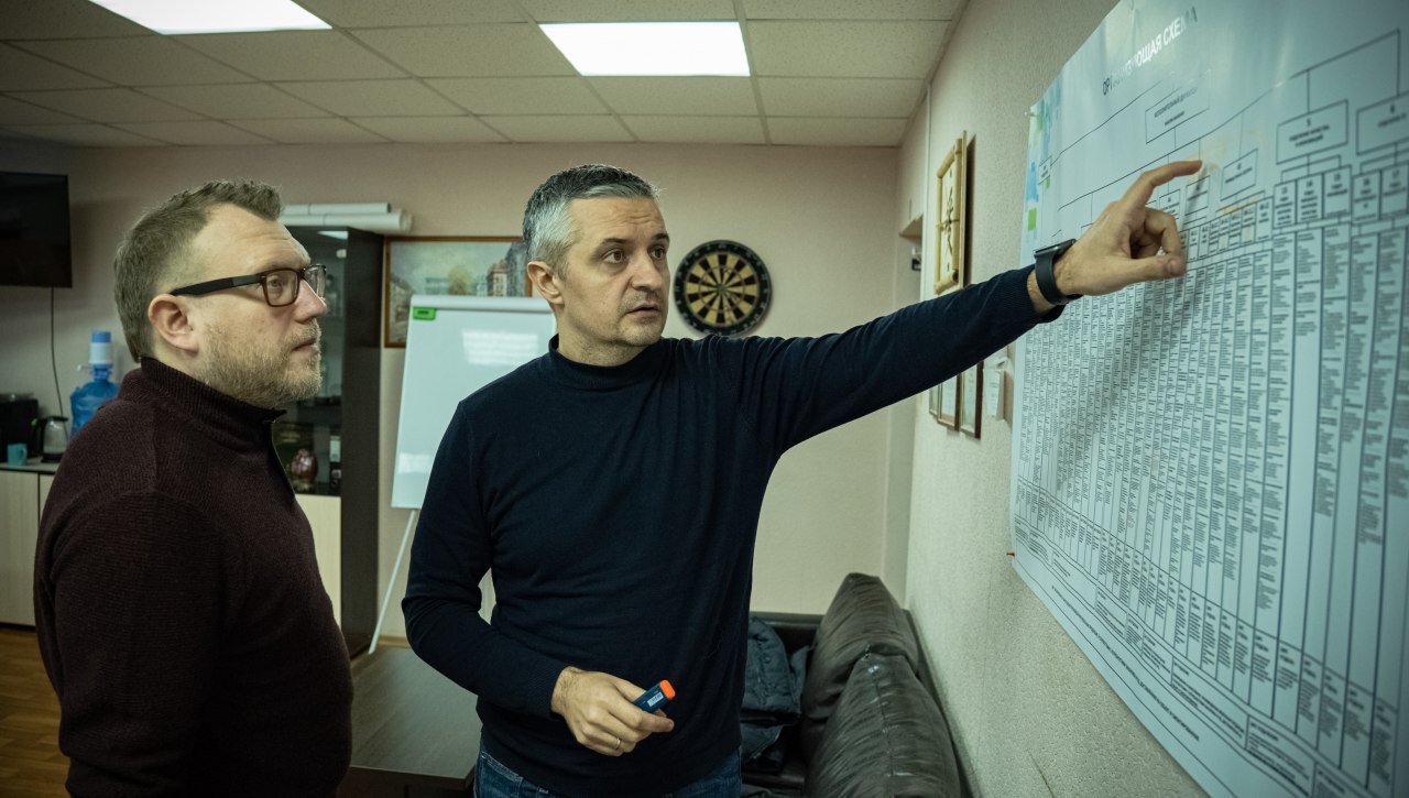 Константин Федоров обсуждает организационную структуру у схемы на стене
