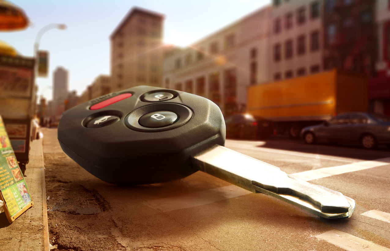 Lost car key lying on the road with a parked car in the background – The stressful moment of losing your only car key