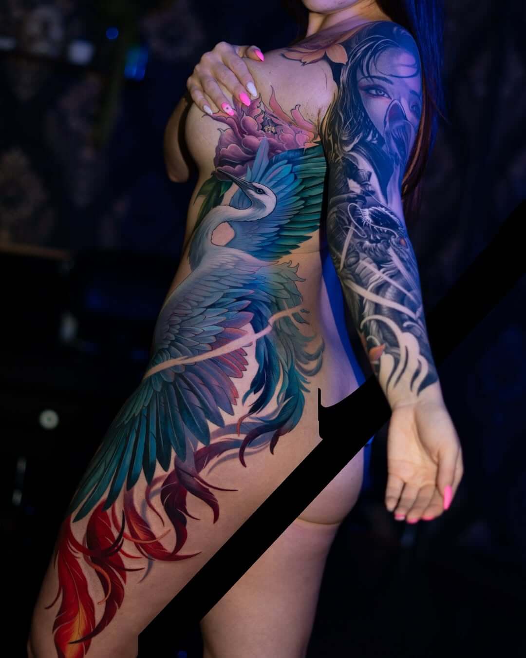 Large side body tattoo for women featuring a realistic white crane with vibrant blue wings and a purple peony flower, Neo-traditional style, colorful torso and hip ink.