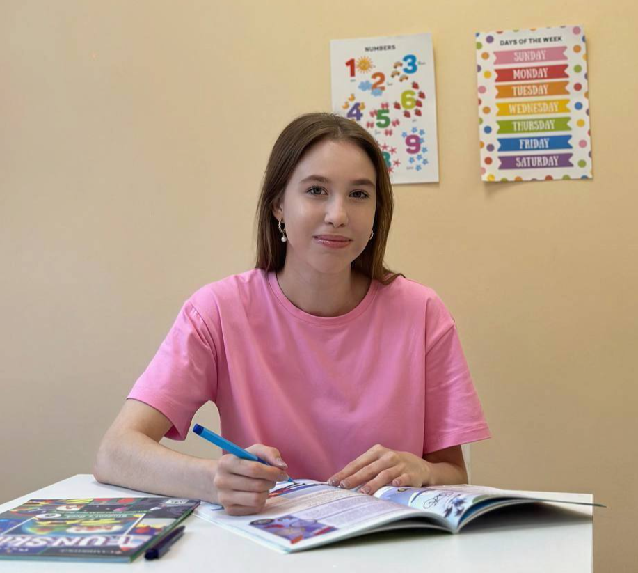 Преподаватель английского и французского Ольга Иванова. Женщина со светлыми волосами до плеч в полосатой кофте белого цвета с бордовыми полосками