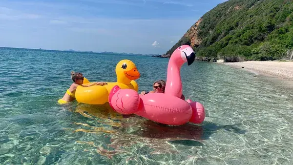 Гости на надувных утке и фламинго в прозрачном море