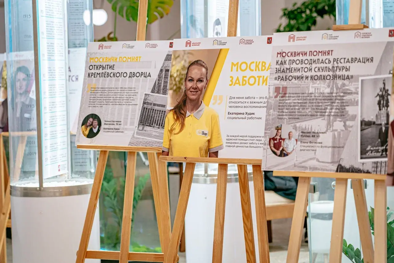 Экспозиция фотовыставки «Москва заботится. Москвичи помнят» ко Дню города. На переднем плане — стенд с социальным работником Екатериной Худик из организации «Мой социальный помощник» и историей реставрации скульптуры «Рабочий и колхозница»