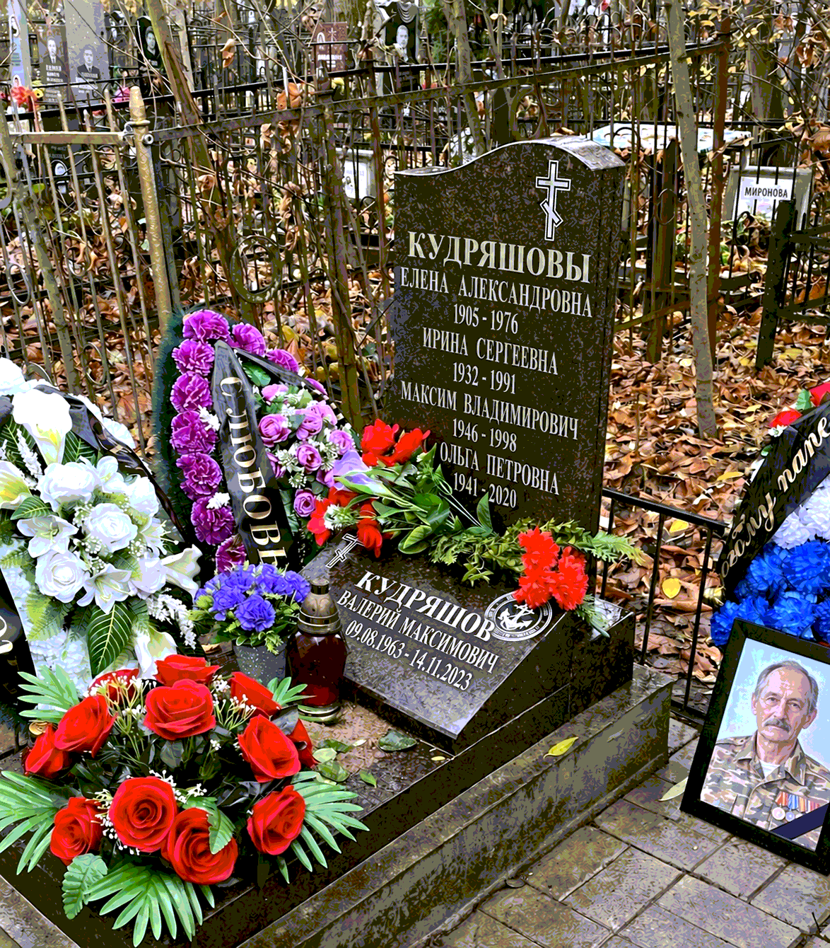 Наклонное надгробие с надписью, крестом и памятным символом среди цветов
