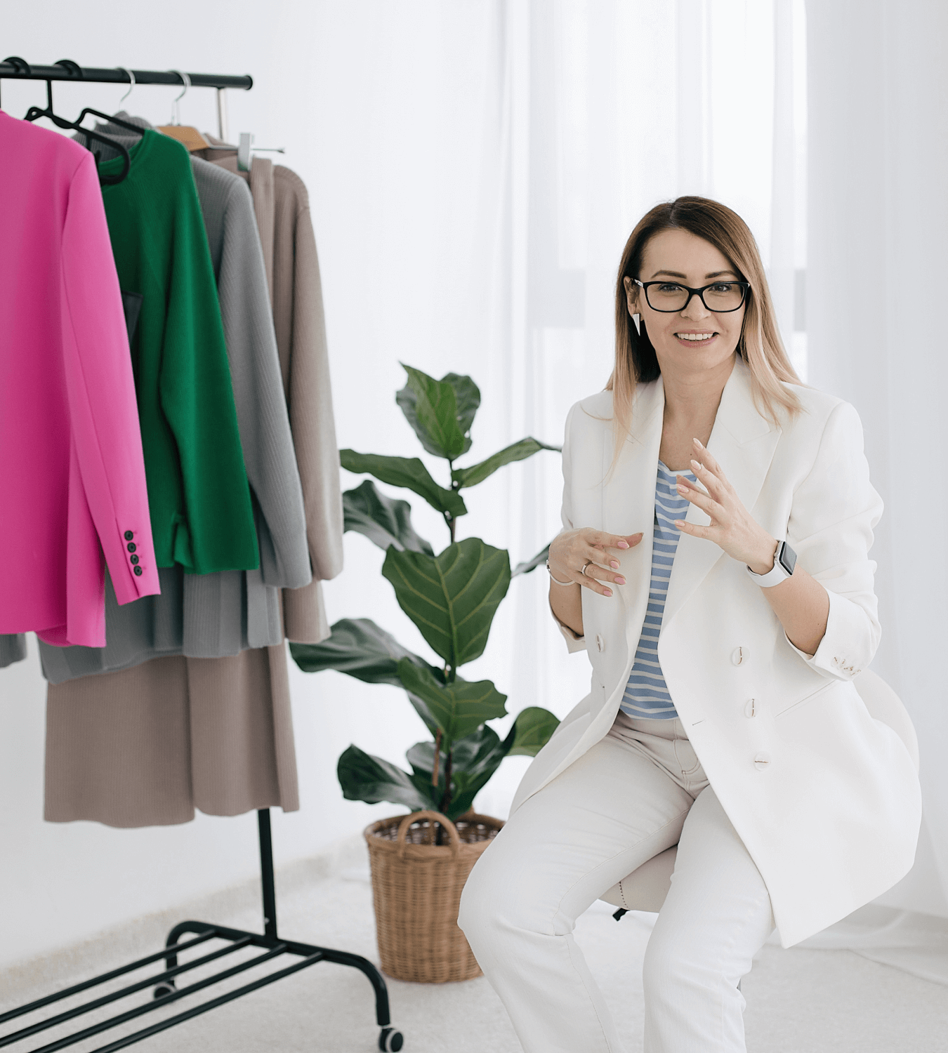 Девушка стилист имиджмейкер сидит на стуле рядом с вешалкой с одеждой