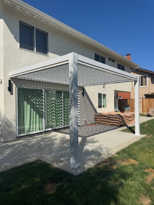 Open motorized pergola louvers casting shade over Huntington Beach patio