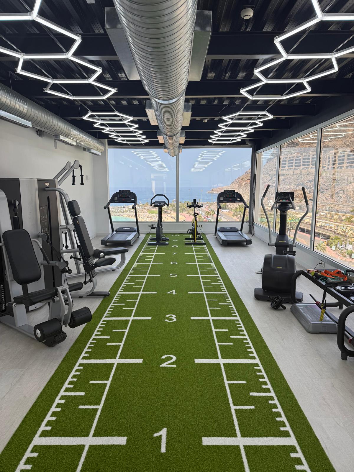 Interno della palestra dell'hotel Amadores View con attrezzature Technogym e vista sulla baia di Amadores.