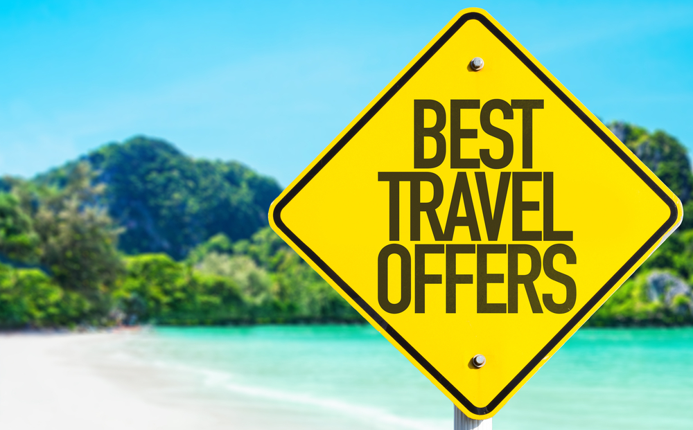 Sign on the beach with a message showing the best travel offers.