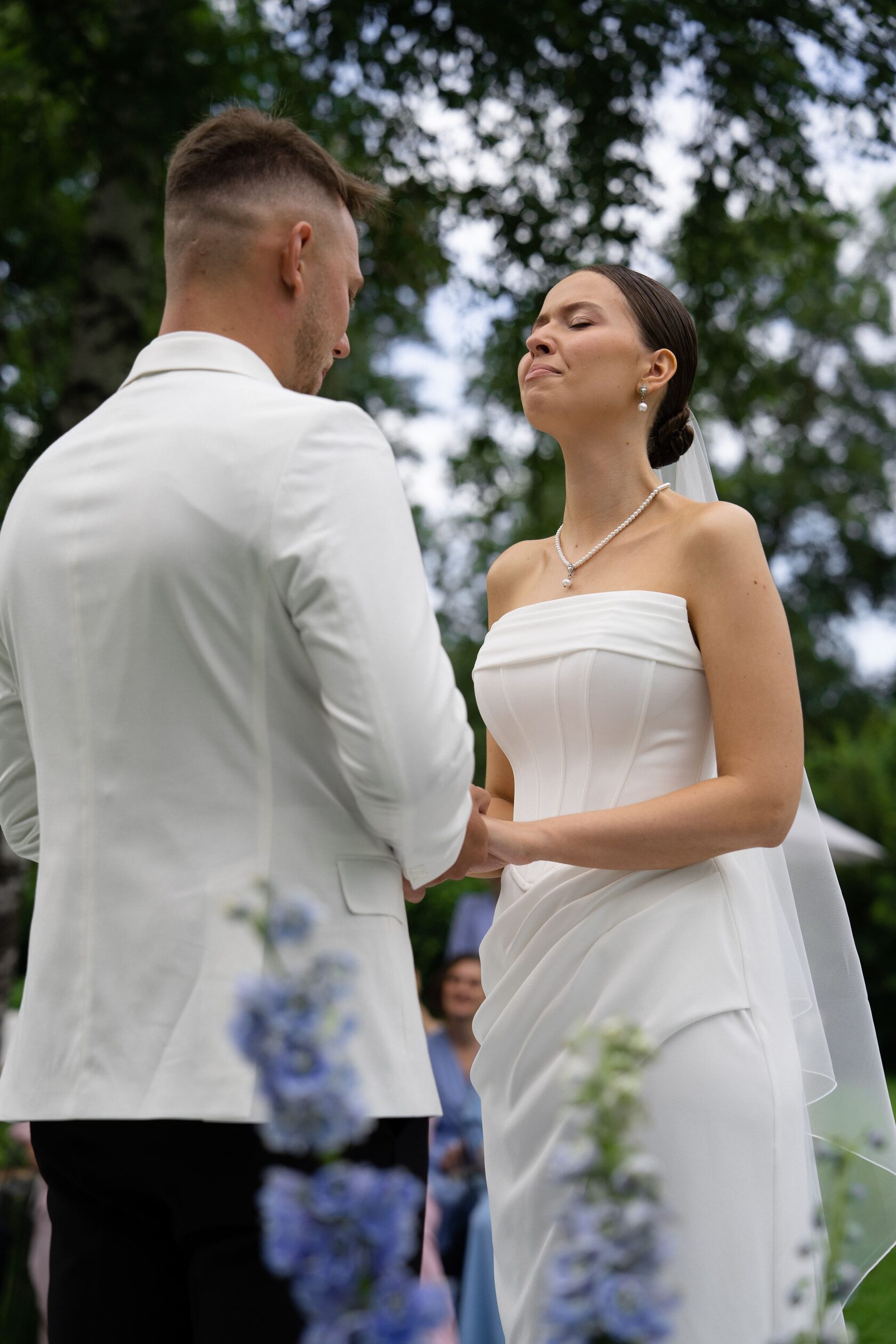 жених и невеста стоят рядом с флористическими свадебными композициями